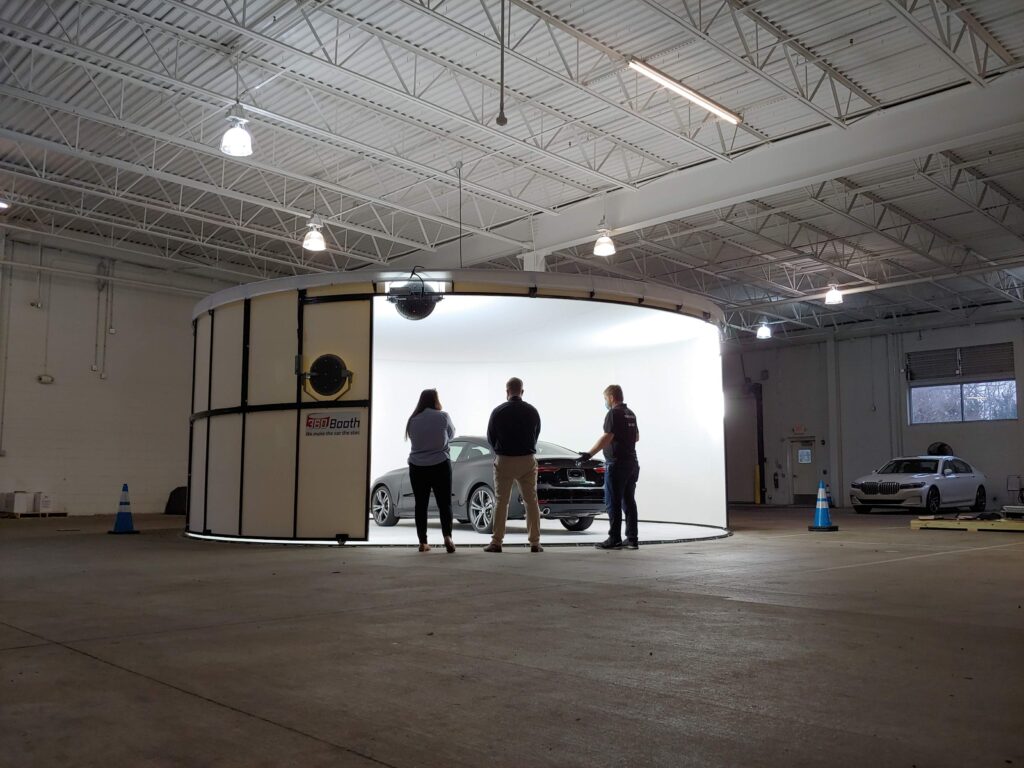 360Booth Vehicle Photo Studio in a dealership warehouse with three people discussing the car inside